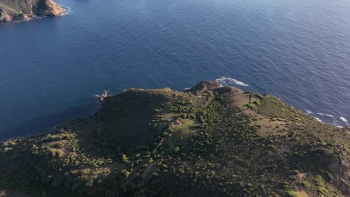 日落时飞越多山的海岸线，可以看到大海、悬崖和绿色的田野。