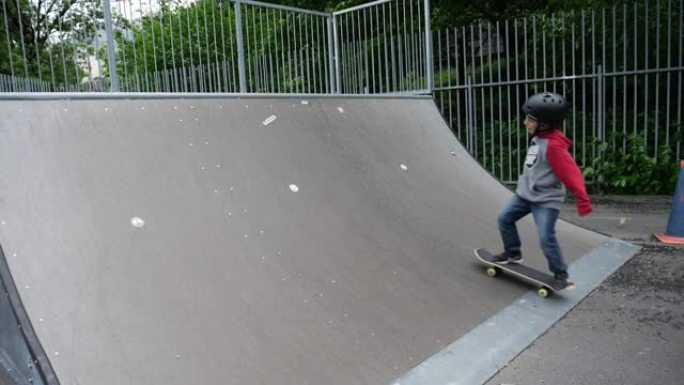 一个小男孩在滑板公园里玩滑板把戏的慢动作镜头