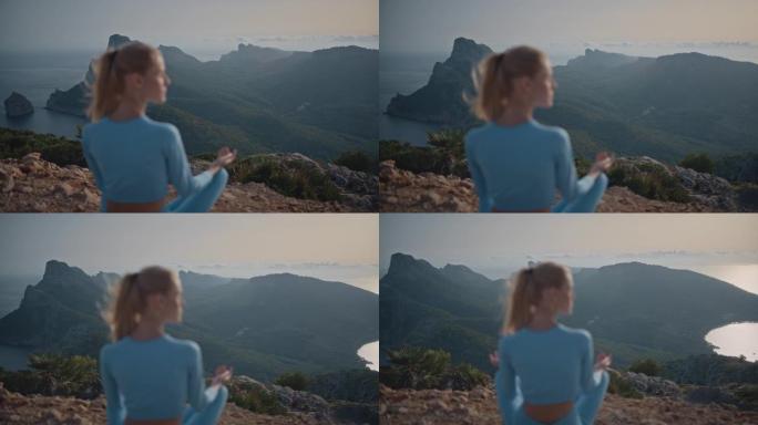 一个与自然。女人在山谷上方岩石悬崖顶上的莲花姿势冥想