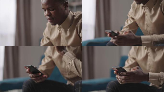 美国黑人正在坐在公寓客厅的智能手机上上网，在社交网络上查看照片