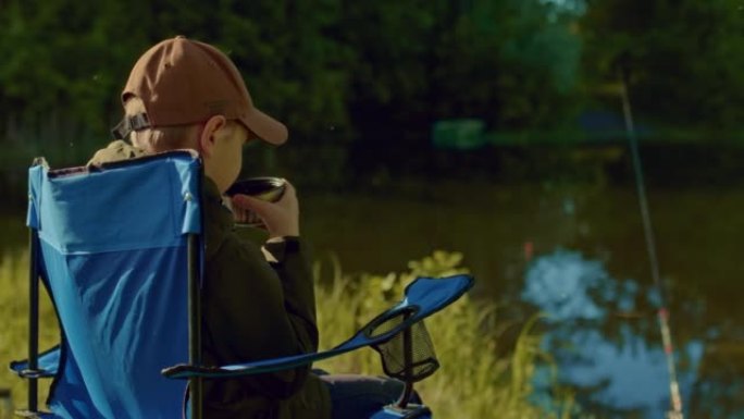 小渔夫正在放松，等待时喝茶咬人，湖水中的钓鱼竿，4K，Prores