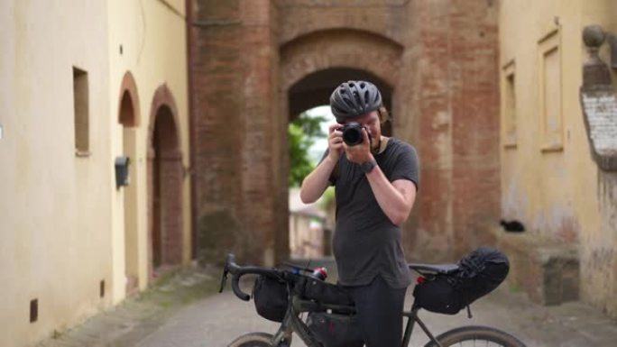 骑自行车的人停下来欣赏风景并在中世纪的小镇拍照
