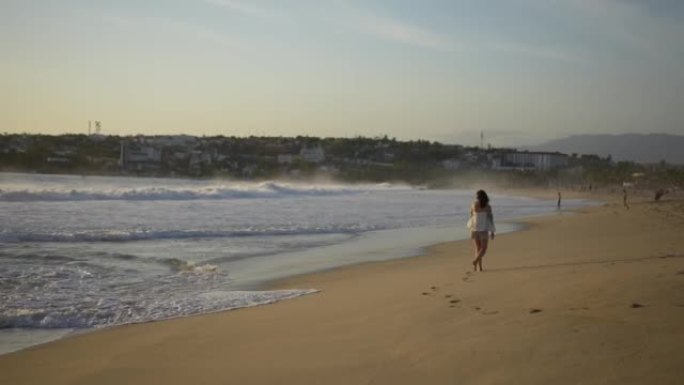 日落时在海滩上散步的女人