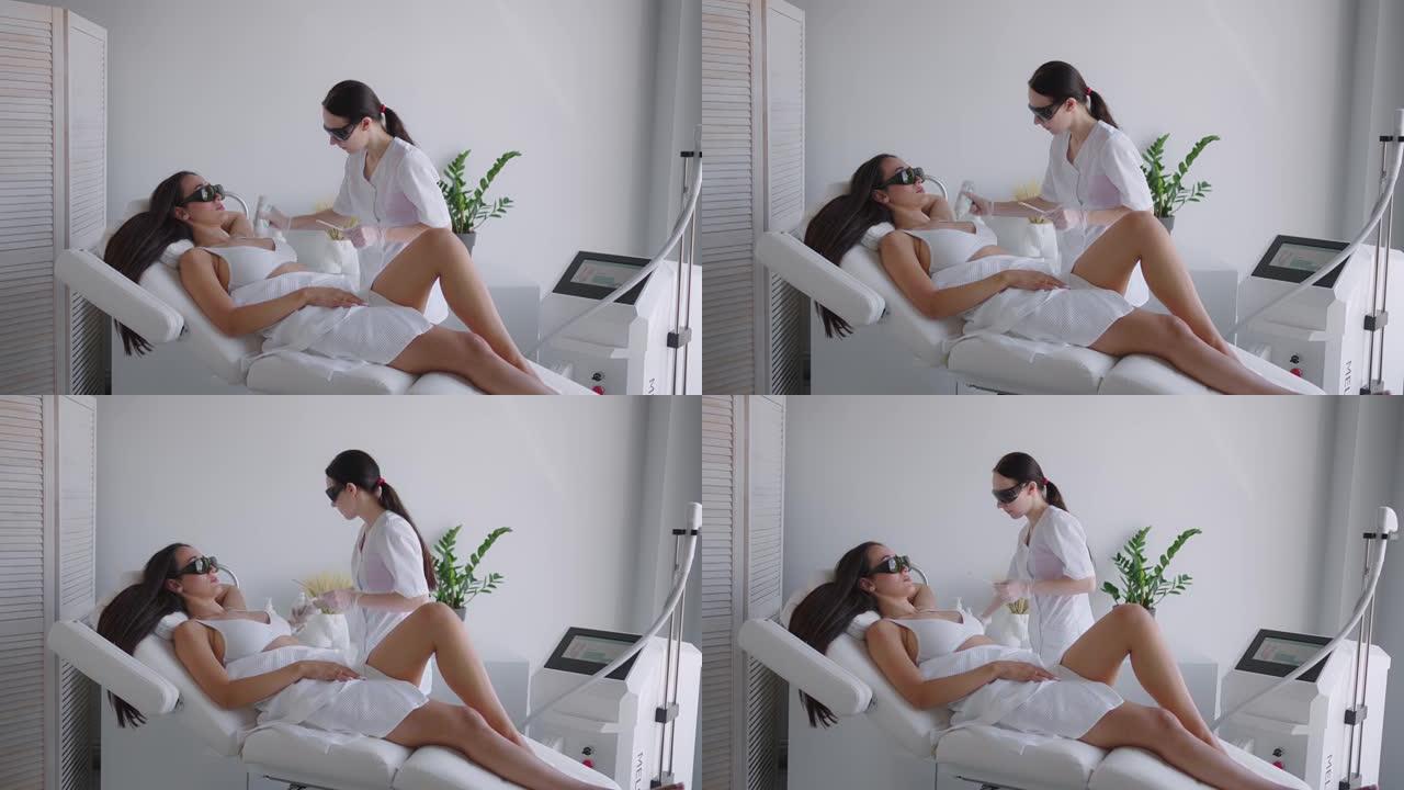 美容师做腋下激光脱毛迷人性感女人躺在医疗沙发上，在美容院微笑。美容师做激光脱毛病人的腋窝。脱毛程序