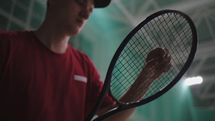 职业男子网球运动员在比赛或训练前正在检查球拍，室内网球场