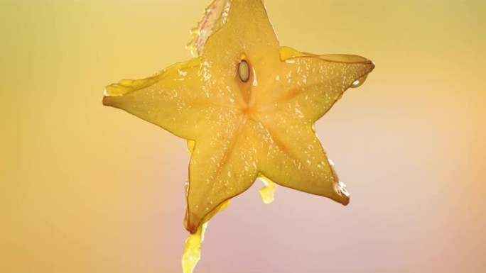 从切成两半的杨桃明星果实中流动的杨桃汁的慢动作宏观拍摄