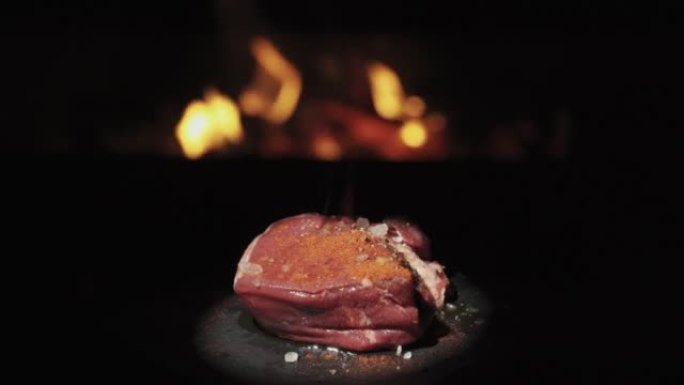 一块牛肉在火的背景下旋转。撒上辣椒粉