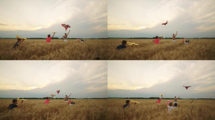 快乐的青少年和小男孩在金黑麦田里玩玩具飞机和放风筝，慢动作