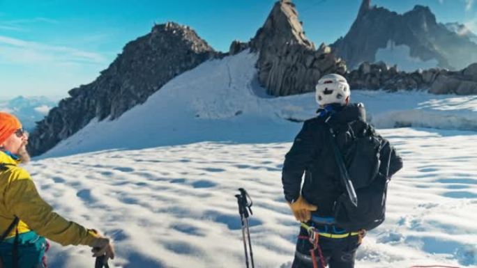 一队登山者沿着冰雪覆盖的斜坡移动。使用绳索和攀爬设备。欧洲阿尔卑斯山