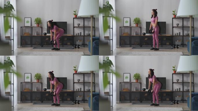 苗条和良好的身体状况，在家训练身体塑形，苗条的女士正在用哑铃做运动