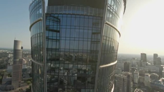映照蓝天的玻璃摩天大楼。FPV无人机转弯并向上移动建筑物