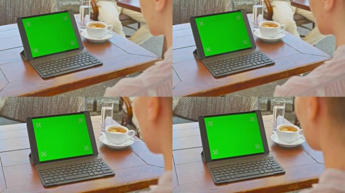 女人坐在咖啡馆里看着她的数字平板电脑的屏幕
