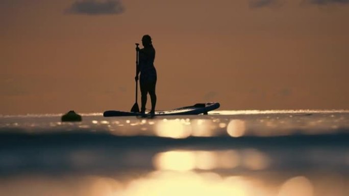 日落时年轻女子划桨