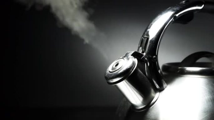 沸腾的钢制银水壶，带有黑色背景上的蒸汽特写哨子。4k原始慢动作视频60 fps。