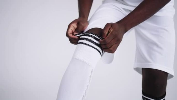 非洲足球运动员正在拉膝盖袜子，特写镜头，穿着专业运动制服