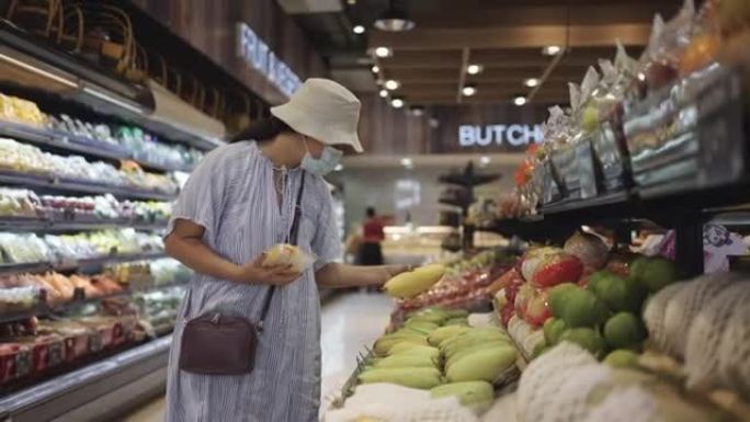 戴帽子和防护口罩的女人在超市购物