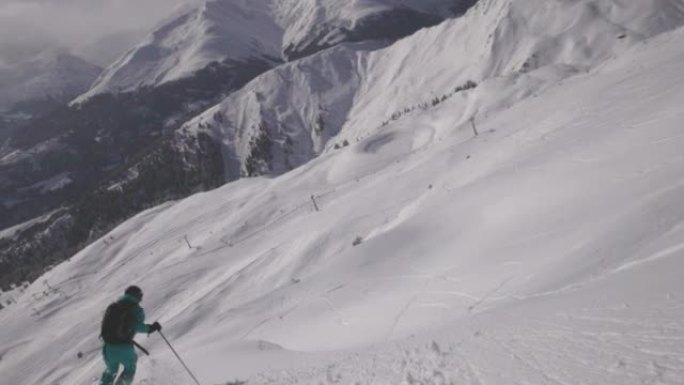 一名滑雪者从白雪皑皑的山坡上下来拍摄后