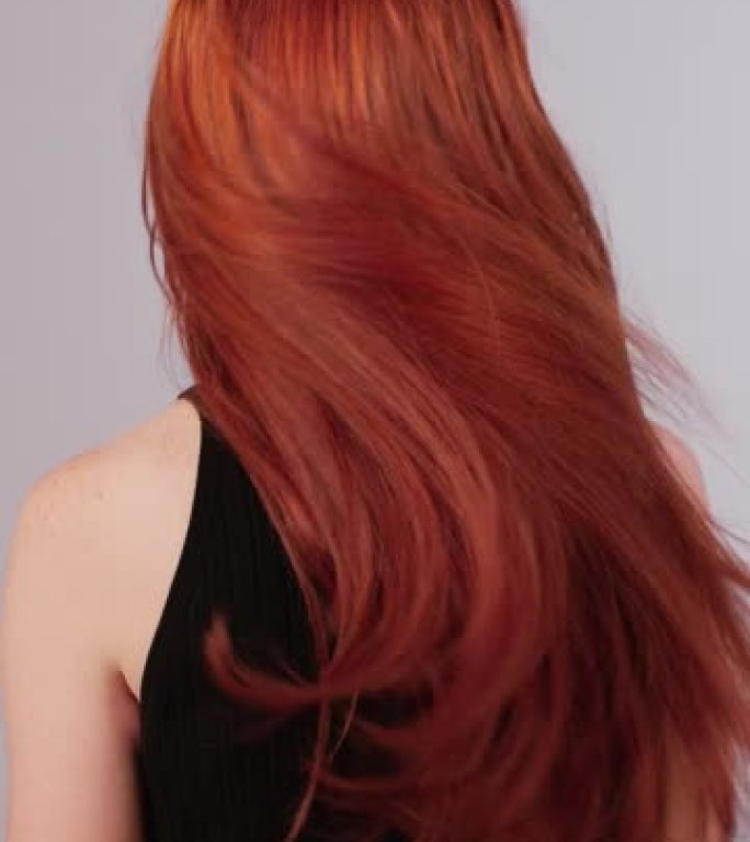 美丽诱人的红发女人扔长发。闪亮的红头发在镜头前移动