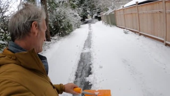 男子在漫长的车道上铲雪