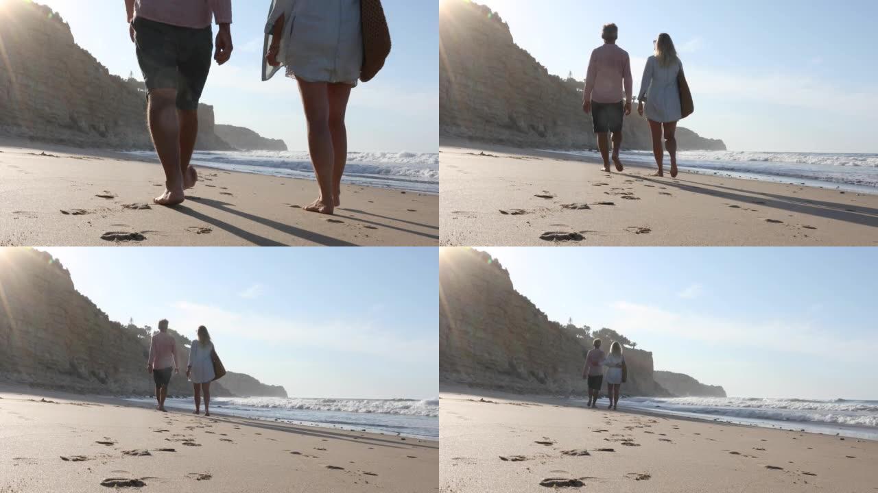 夫妇沿着空荡荡的海滩散步，日出