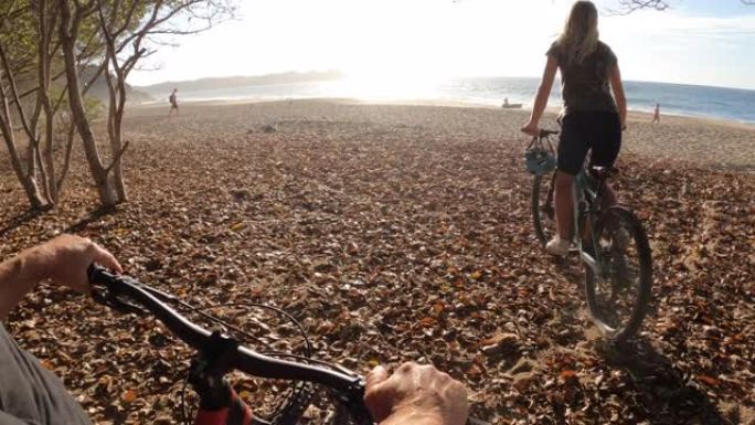 POV pat自行车车把给骑自行车去海滩的年轻女子