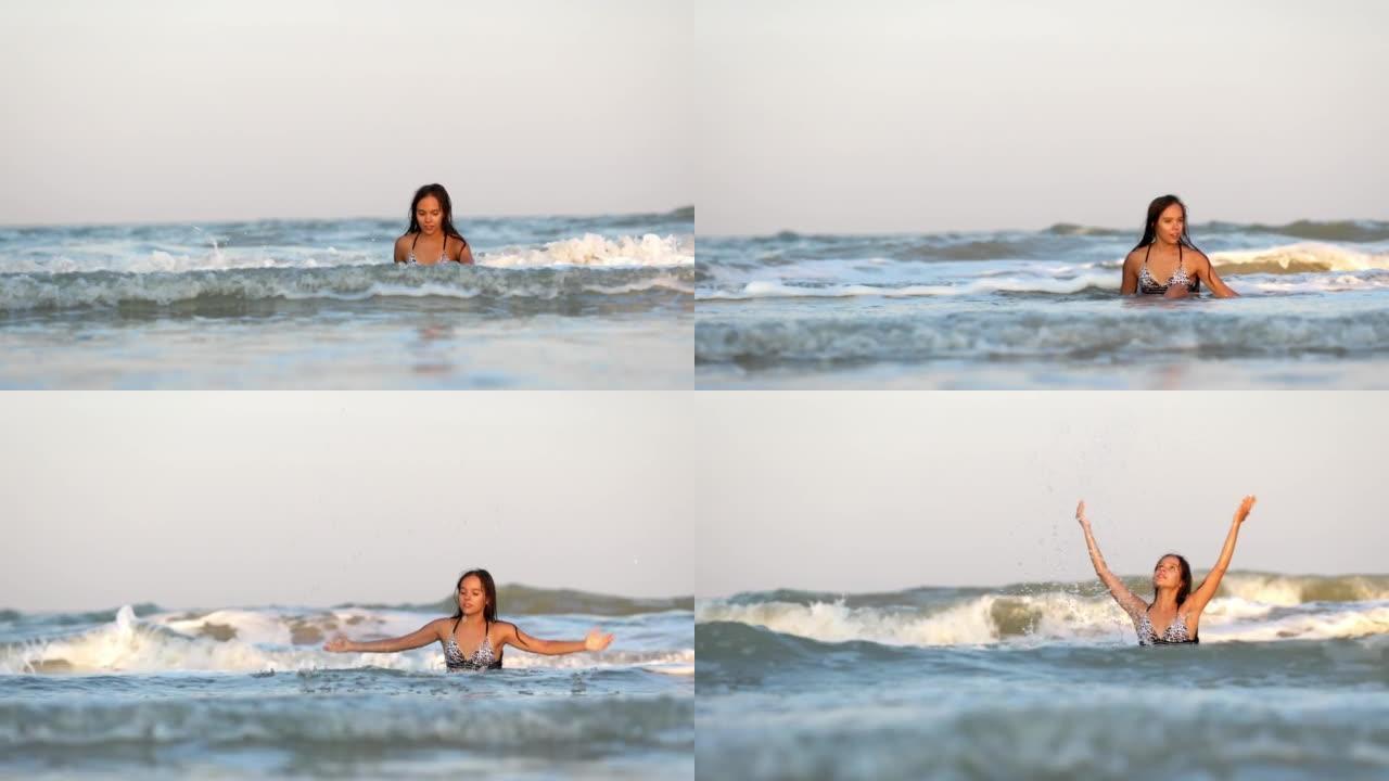 穿着豹纹泳衣的湿头发的女孩坐在海里时溅水