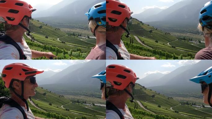 骑自行车的夫妇欣赏葡萄园和山脉的景色