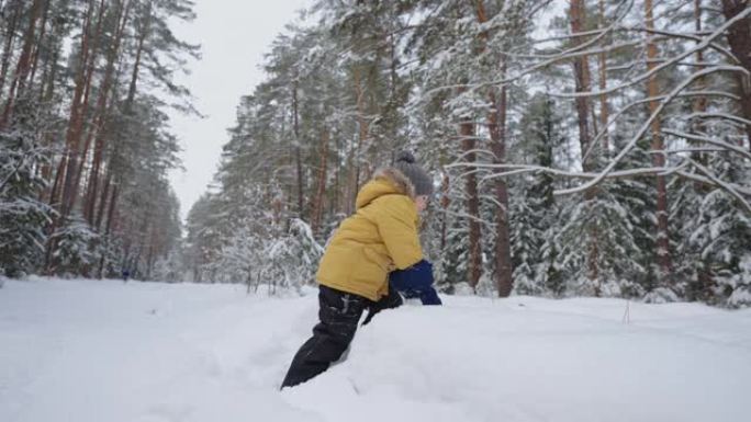 可爱的小男孩冬天在森林里玩雪，穿着暖和夹克的快乐蹒跚学步的孩子微笑着