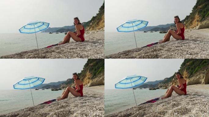 石滩上的女人在沙滩伞下放松。享受大海