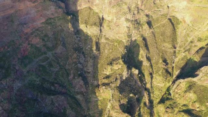 巨大的无人机飞行在日落照亮的悬崖上，岩石另一边的阴影和雾。4k空中拍摄。