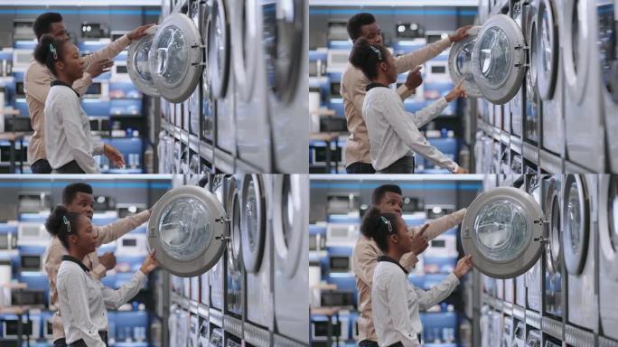 配偶在家电商店选择洗衣机，年轻的非洲裔男女正在观看展览样本