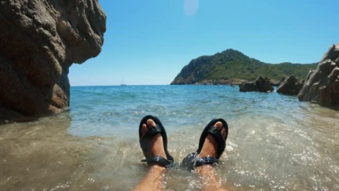 夏季撒丁岛空旷的海滩上的男人的POV脚视图