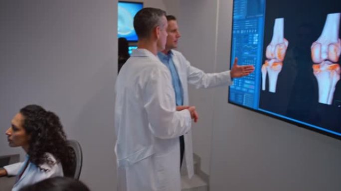 两名男性放射科医生分析灯箱上膝盖的MRI图像