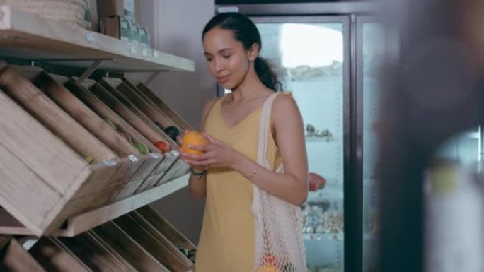 女人在环保和免费塑料杂货店购买新鲜橙子。消费者闻到并选择有机水果和蔬菜来健康饮食。使用可重复使用的袋