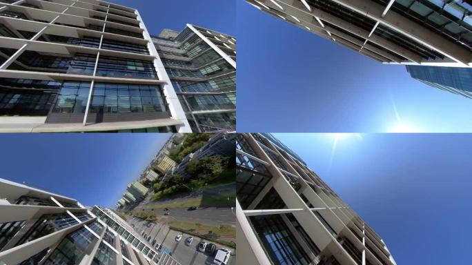 360度视图。城市景观与现代化的玻璃建筑对抗蓝天。FPV无人机以圆周运动飞行