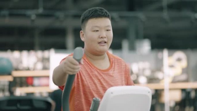 一个肥胖的亚洲男孩正在使用健身器材