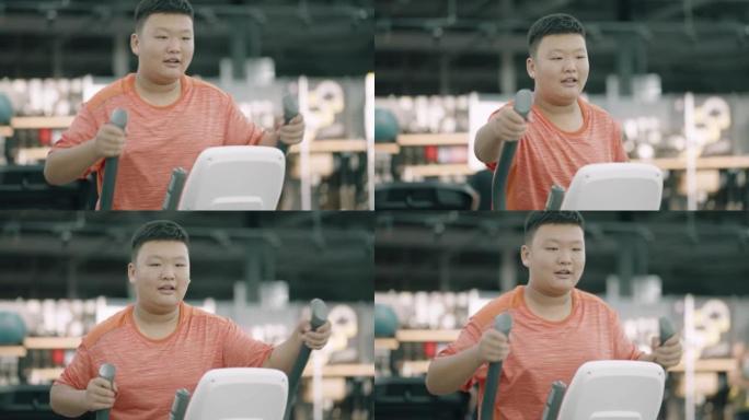 一个肥胖的亚洲男孩正在使用健身器材