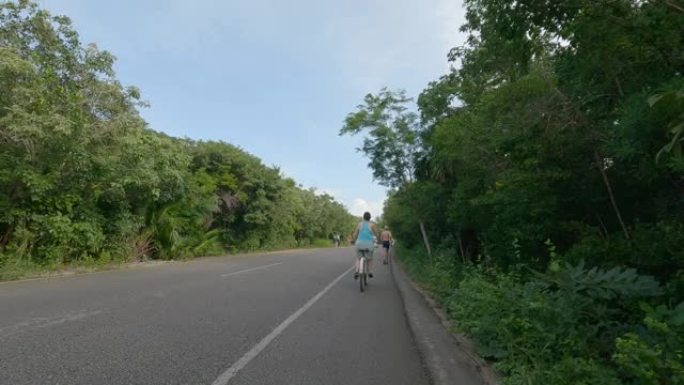 女人沿着丛林道路骑自行车