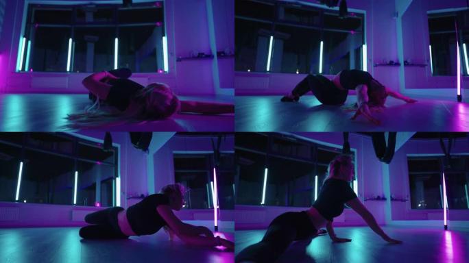 一个女人在霓虹灯的工作室里跳舞，表演着慢动作的伸展和跳舞的优美练习和动作