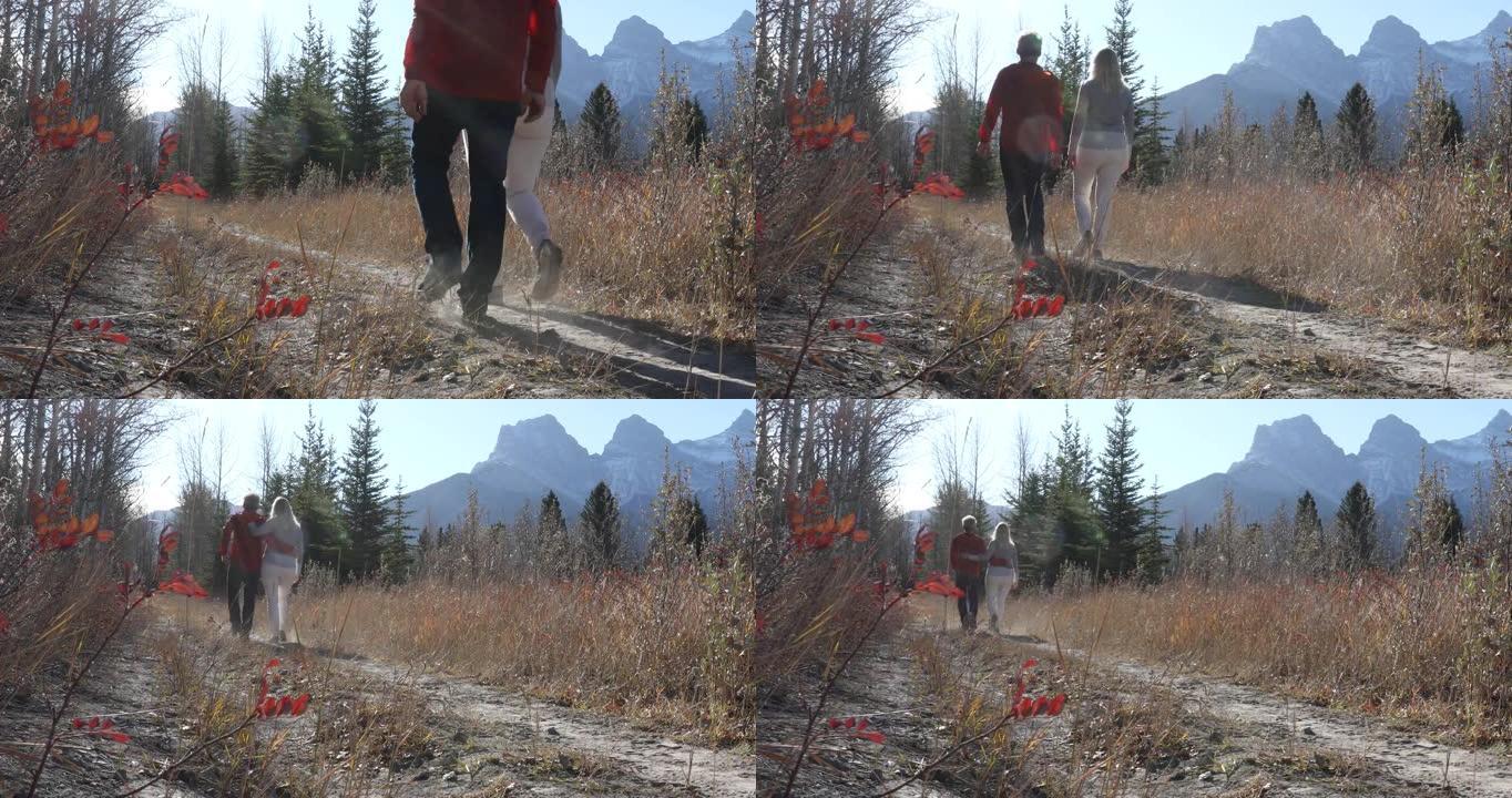 成熟的夫妇沿着秋天的高山小径行走，遥远的山脉