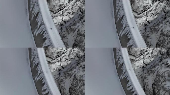 空中无人机拍摄的一名男子穿越山区积雪覆盖的大坝
