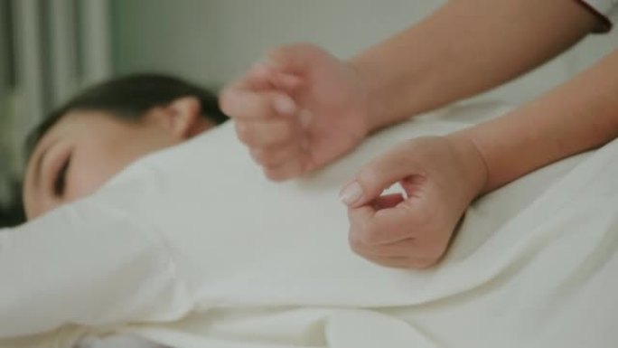 女人手作为泰国按摩治疗师按摩背部，预防背部疼痛。