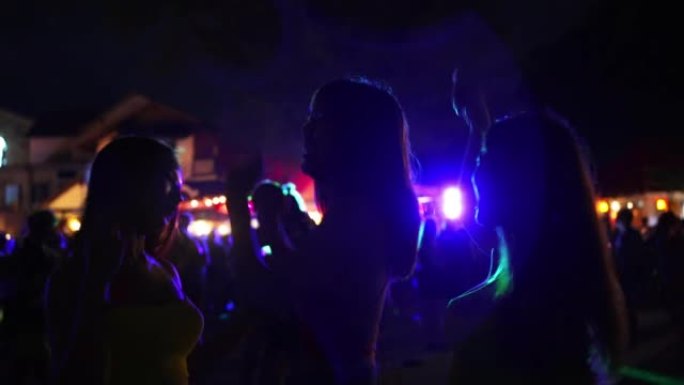 一群亚洲女人在热带岛屿海滩的满月之夜派对上一起跳舞。