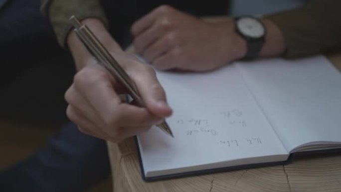 一个年轻人在笔记本上写字的细节照片
