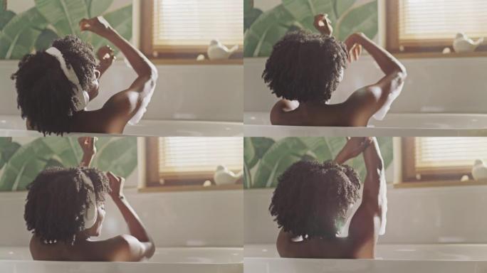 美丽的非洲民族妇女在现代浴室放松。听音乐和玩泡沫