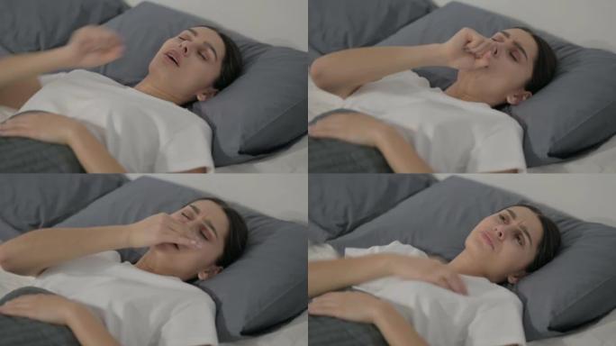 西班牙裔妇女在床上睡觉时咳嗽
