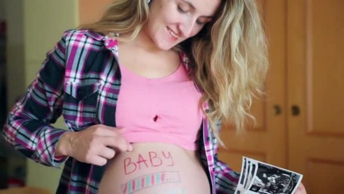 微笑的女人用婴儿装填铭文关心她怀孕的肚子