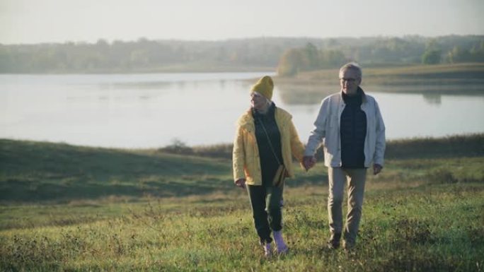 充满爱心的老年夫妇一起在湖边散步和牵手