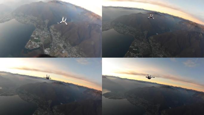 日落时分，天空潜水员在湖泊和山脉上方自由落体