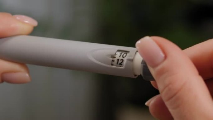 一名妇女手持胰岛素笔的特写镜头，手中握有长效胰岛素